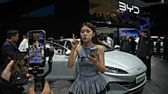 Modell beszél egy BYD autó előtt a kínai autóshow-n