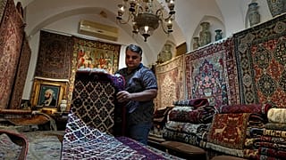 Iranian carpet shop owner Ali Faez works at his shop at the traditional bazaar of the city of Kashan, about 152 miles (245 km) south of the capital Tehran, Iran.