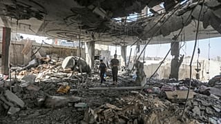 Palestinians stand in the ruins of the Chahine family home, after an overnight Israeli strike that killed at least two adults and five boys and girls in Rafah