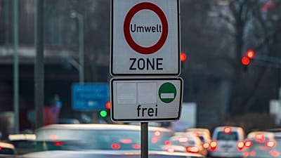 Os carros passam por uma placa onde se lê 'zona ambiente' e permitindo a entrada apenas para carros com baixas emissões na Alemanha.