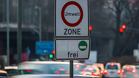 Os carros passam por uma placa onde se lê 'zona ambiente' e permitindo a entrada apenas para carros com baixas emissões na Alemanha.