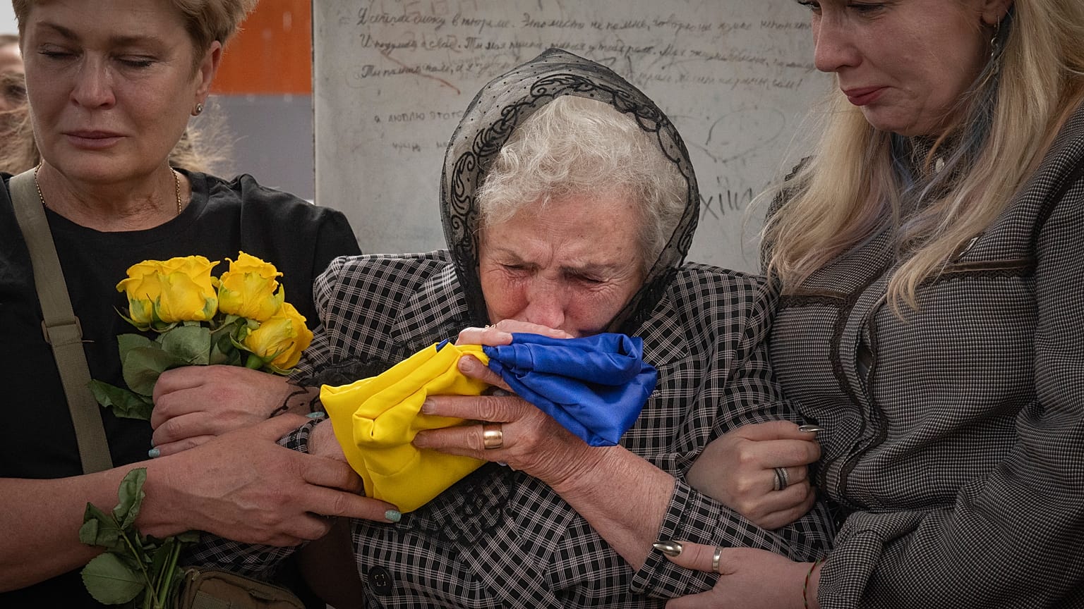 Мать погибшего украинского военного целует флаг Украины во время похоронной процессии в Киеве 6 мая