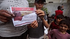 Palestinians hold leaflets dropped by Israeli planes calling on them to evacuate ahead of an Israeli military operation in Rafah, southern Gaza Strip, Monday, May 6, 2024. 