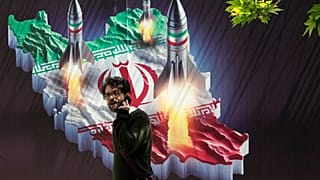 Un homme passe devant une bannière montrant des missiles lancés depuis une carte iranienne à Téhéran, le 19 avril 2024.