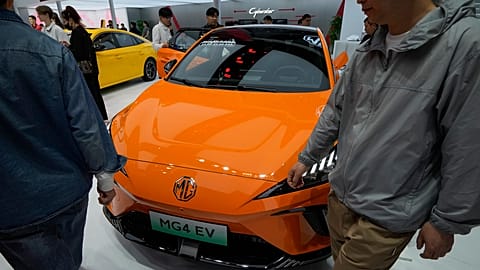 Visitors walk by a MG4 EV car on display during the Auto China 2024 in Beijing