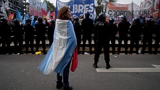 A demonstrator stands wrapped in an Argentine flag during a protest against food scarcity at soup kitchens and economic reforms proposed by President Javier Milei in Buenos A