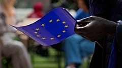 Un homme tient un drapeau de l'Union européenne alors qu'il marche devant le bâtiment de la Commission européenne lors des célébrations de la Journée de l'Europe à Bruxelles, le 4 mai 2024.