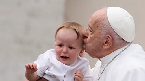 Pope Francis kisses a child at the end of his weekly general audience in St. Peter's Square, at the Vatican, Wednesday, May 8, 2024