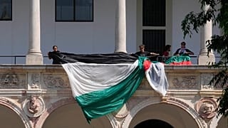 Estudantes e ativistas desenrolam uma bandeira palestiniana enquanto montam um acampamento no pátio da Universidade Estatal de Milão