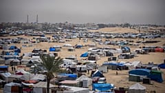 Les Palestiniens déplacés par l'offensive aérienne et terrestre israélienne sur la bande de Gaza marchent dans un camp de tentes de fortune à Rafah, le 10 mai 2024.