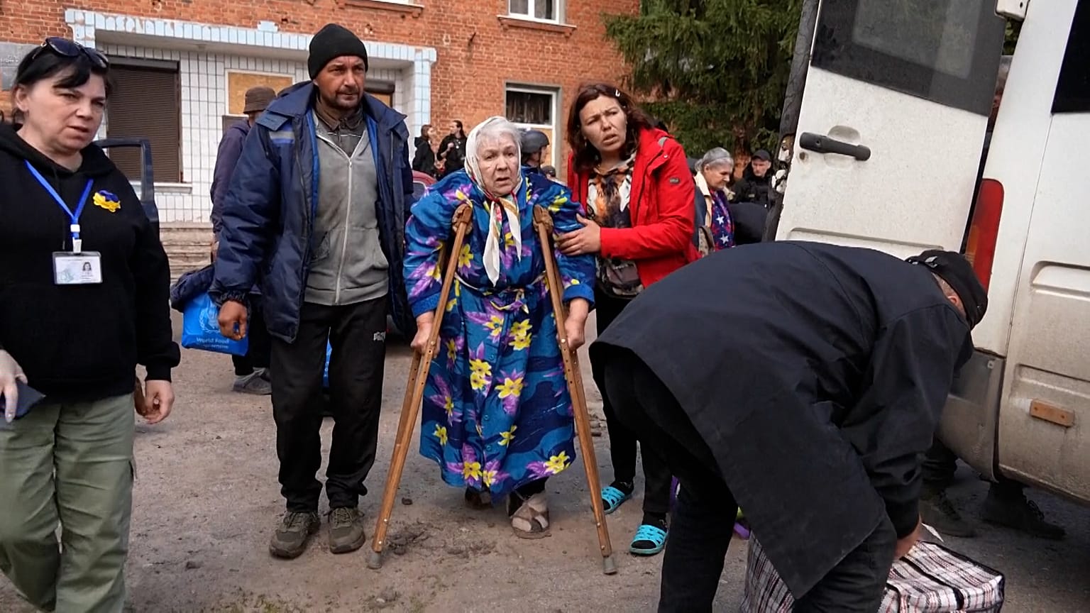 Elderly woman is helped onto the bus evacuating people from the area