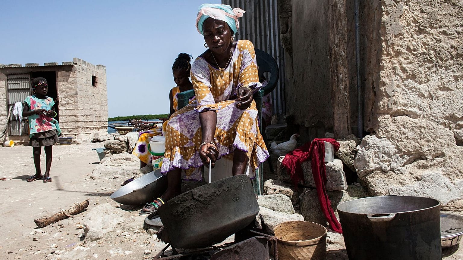 Uma mulher assa amendoins no exterior da sua casa na ilha de Diamniadio, no Senegal.