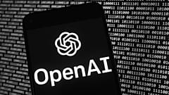 El logotipo de OpenAI aparece en un teléfono móvil frente a una pantalla de ordenador con datos binarios aleatorios, el jueves 9 de marzo de 2023, en Boston.