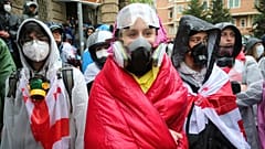 Des manifestants portant des masques à gaz se tiennent près du bâtiment du Parlement lors d'une manifestation de l'opposition contre la "loi russe" dans le centre de Tbilissi, en Géorgie, le lundi 13 mai 2024.