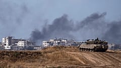 Gazze sınırında bulunan bir İsrail tankı ve kentin içinde bombardıman sonrası yükselen siyah dumanlar