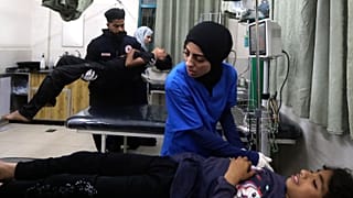 Palestinian medics treat a wounded person as the other one carries a young wounded in the Israeli bombardment of the Gaza Strip at the Kuwaiti Hospital in Rafah refugee camp,