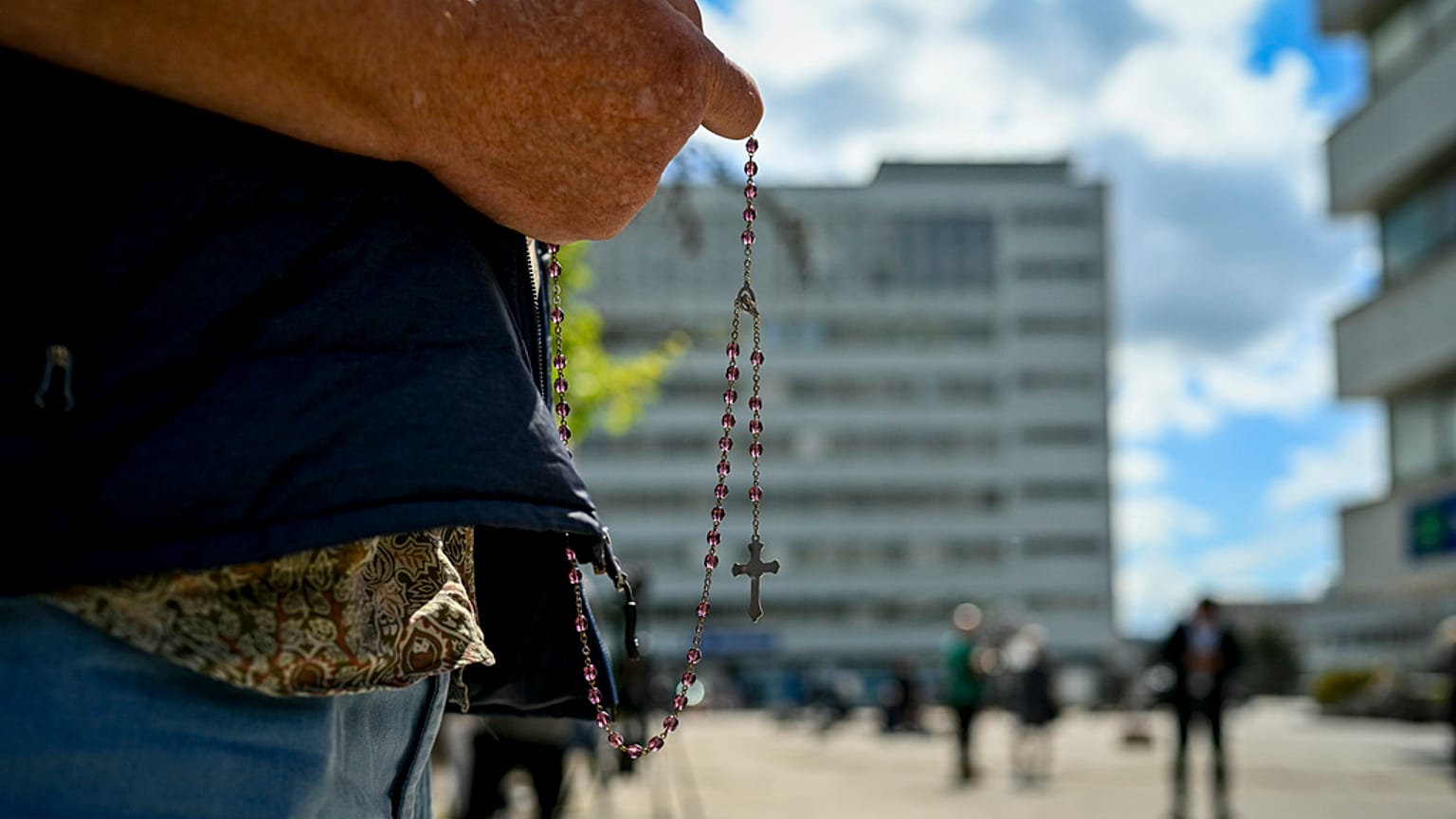 A man prays holding Slovakia's flag outside the F. D. Roosevelt University Hospital, where Prime Minister Robert Fico is treated in Banska Bystrica, Thursday, May 16, 2024.