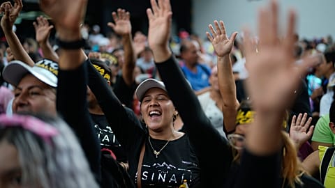 Evangelical Christinas raise their hands in prayer during a march in defense of the original family model marking Family Day