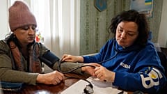 Ein medizinischer Freiwilliger von FRIDA Ukraine prüft den Blutdruck eines Patienten.