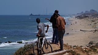 Palestinesi osservano una nave al largo della costa di Gaza, vicino a un molo galleggiante costruito dagli Stati Uniti per le consegne di aiuti (16 maggio 2024)