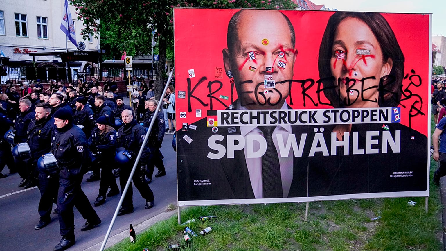 Police officers walk past a poster of the Social Democrats for the European elections during the revolutionary May Day demonstration in Berlin, Germany, Wednesday, May 1, 2024