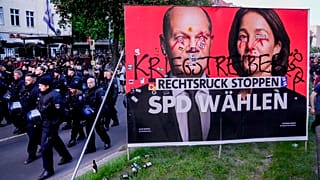Police officers walk past a poster of the Social Democrats for the European elections during the revolutionary May Day demonstration in Berlin, Germany, Wednesday, May 1, 2024