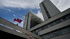 Мужчина размахивает национальным флагом у здания больницы, где проходит лечение премьер-министр Роберт Фицо, раненый в результате покушения, Братислава, 16 мая 2024 г.