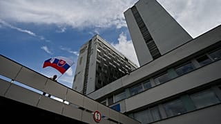 Мужчина размахивает национальным флагом у здания больницы, где проходит лечение премьер-министр Роберт Фицо, раненый в результате покушения, Братислава, 16 мая 2024 г.