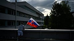 Un hombre ondea la bandera nacional de Eslovaquia frente al hospital donde tratan al primer ministro, Robert Fico