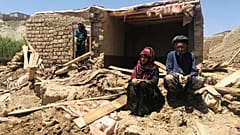 زوجان أفغانيان أمام منزلهما المتضرر بعد فيضانات غزيرة في مقاطعة غور بغرب أفغانستان، 18 مايو 2024.