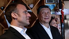 Chinese President Xi Jinping, right, watches French President Emmanuel Macron in a restaurant, Tuesday, May 7, 2024
