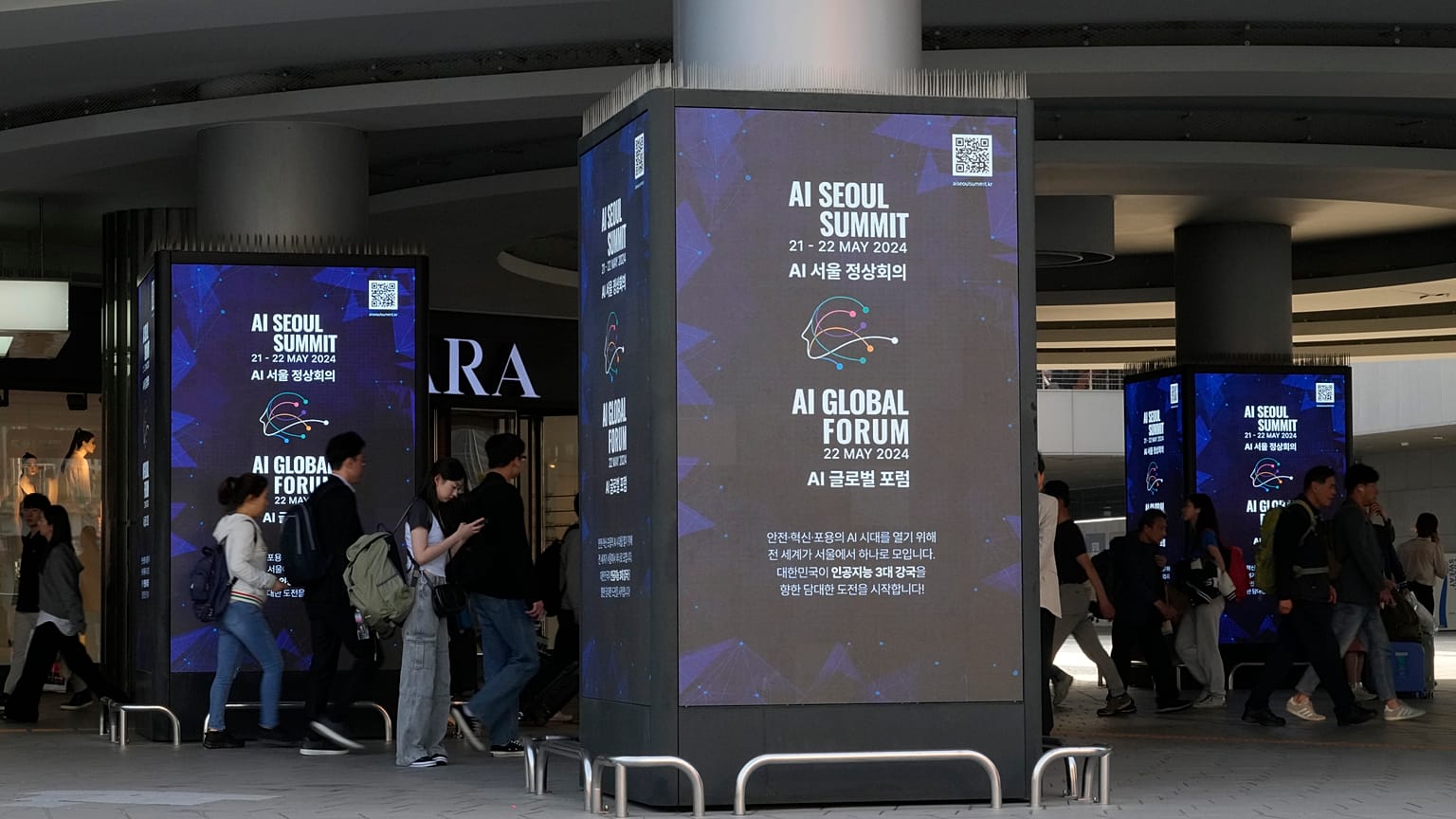 People pass by screens announcing the upcoming AI Seoul Summit in Seoul, South Korea.