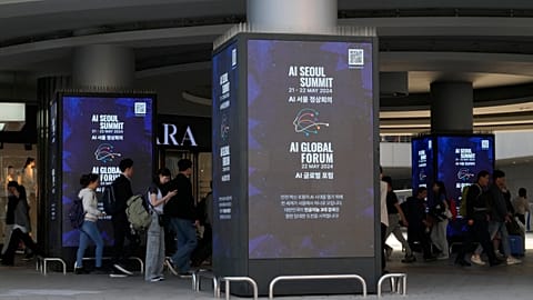 People pass by screens announcing the upcoming AI Seoul Summit in Seoul, South Korea.