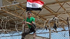  فلسطيني يتسلق سياجًا رفع عليه العلم المصري خلال مظاهرة تطالب مصر بإعادة فتح معبر رفح الحدودي في رفح، جنوب قطاع غزة، الاثنين، 16 سبتمبر، 2013.