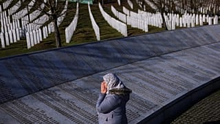 Bosnalı Müslüman bir kadın, Srebrenitsa Anma Merkezi'nde, Srebrenitsa soykırımında öldürülenlerin isimlerinin yazılı olduğu anıtın yanında dua ediyor