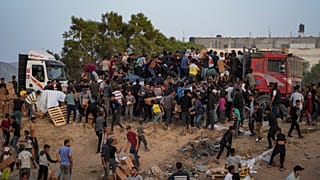 Palestinians are storming trucks loaded with humanitarian aid brought in through a new U.S.-built pier, in the central Gaza Strip, Saturday, May 18, 2024. 