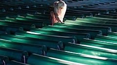 Egy nő zokog a srebrenicai népirtás áldozatainak koporsói mellett