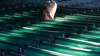 Egy nő zokog a srebrenicai népirtás áldozatainak koporsói mellett