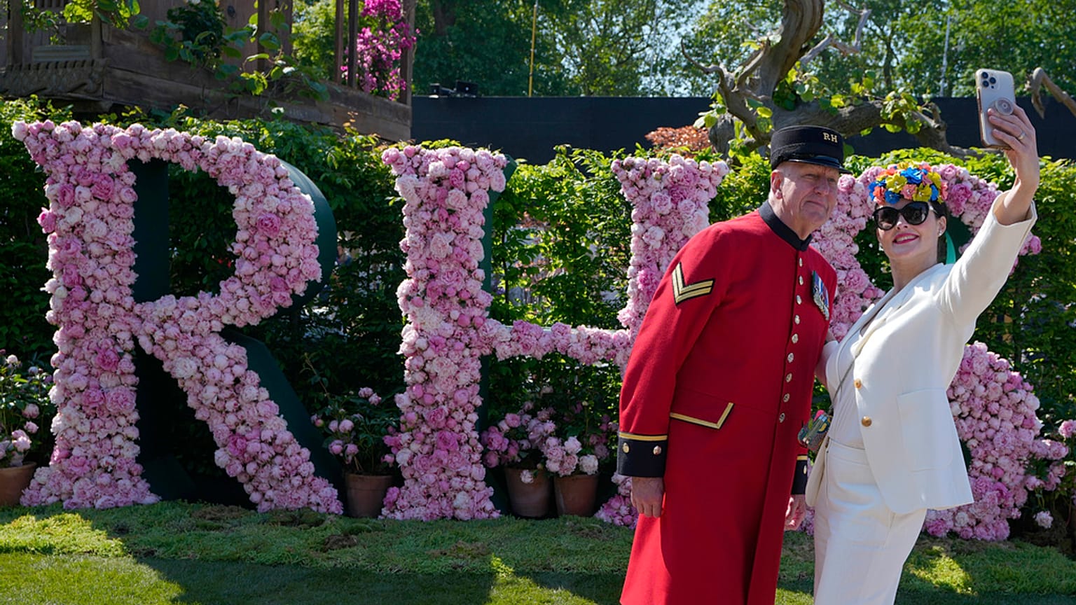 Blooming lovely: A visitor wearing floral themed headwear takes a selfie with Chelsea Pensioner Norman Bareham at the Chelsea Flower Show in London