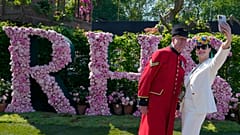 Blooming lovely: A visitor wearing floral themed headwear takes a selfie with Chelsea Pensioner Norman Bareham at the Chelsea Flower Show in London