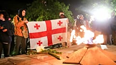 Demonstranten mit einer georgischen Flagge vor einer ewigen Flamme auf dem Heldenplatz in Tfilis, 14. Mai 2024