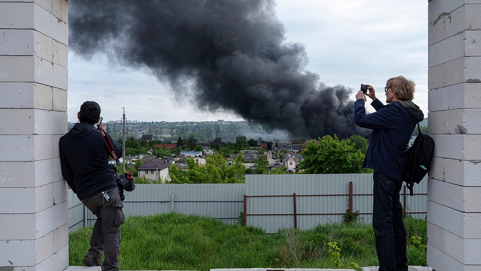 Foreign journalists report from an observation point while smoke rises after a Russian attack in Kharkiv, Ukraine, Friday, May 17, 2024.
