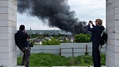 Jornalistas estrangeiros fazem uma reportagem a partir de um ponto de observação enquanto se levanta fumo após um ataque russo em Kharkiv, na Ucrânia, na sexta-feira, 17 de maio de 2024.