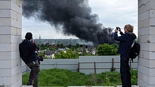 Giornalisti stranieri riferiscono da un punto di osservazione mentre si alza del fumo dopo un attacco russo a Kharkiv, Ucraina, venerdì 17 maggio 2024.