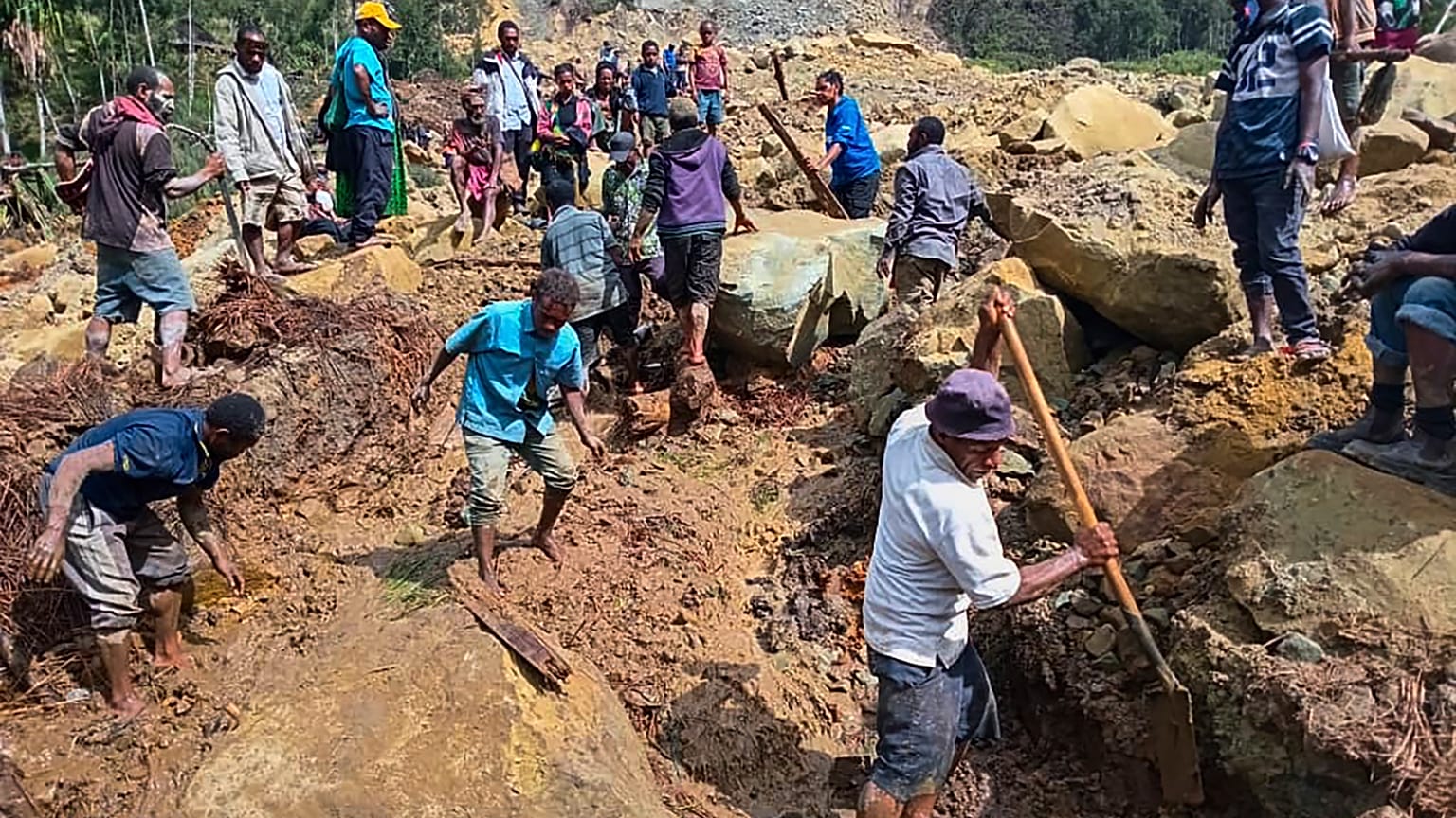 Köylüler 26 Mayıs 2024 Pazar günü Papua Yeni Gine'nin dağlık bölgesindeki Yambali'de meydana gelen toprak kaymasını araştırıyor.
