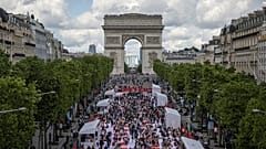 Des personnes déjeunent dans le cadre d'un pique-nique géant sur les Champs-Elysées, devant l'Arc de Triomphe, organisé par le Comité Champs-Élysées, dimanche 26 mai 2024
