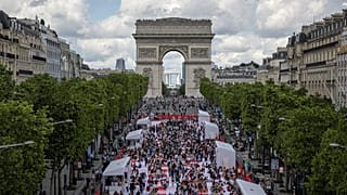 Des personnes déjeunent dans le cadre d'un pique-nique géant sur les Champs-Elysées, devant l'Arc de Triomphe, organisé par le Comité Champs-Élysées, dimanche 26 mai 2024