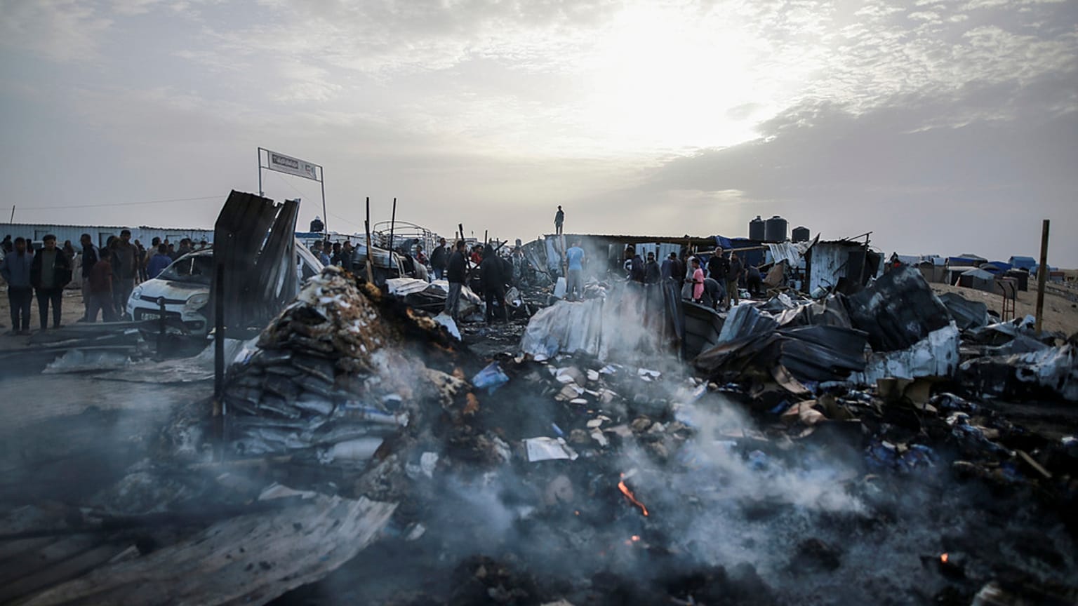 Palestinesi osservano la distruzione della tendopoli in cui erano sfollati, causata da un attacco israeliano a ovest di Rafah, nella Striscia di Gaza (27 maggio 2024)