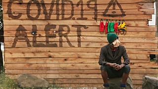 In this June, 24, 2020, file photo, a man sells face masks for use to curb the spread of the coronavirus outside a makeshift shop in Harare, Zimbabwe.