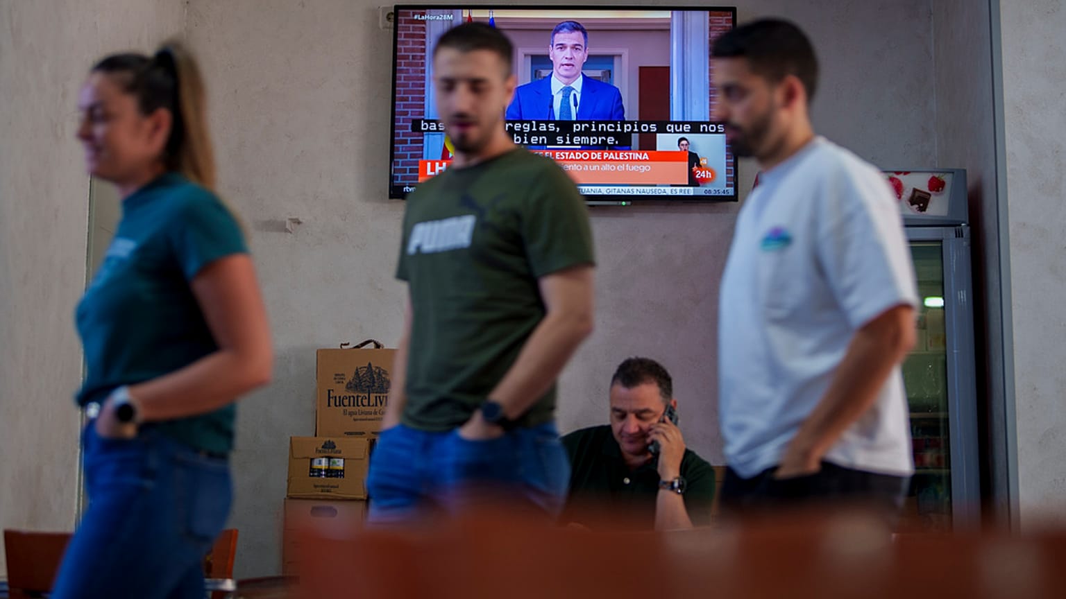 Kunden stehen in einem Restaurant, während der spanische Premierminister Pedro Sanchez in einer Fernsehsendung in Spanien, am Dienstag, 28. Mai 2024, auftritt.
